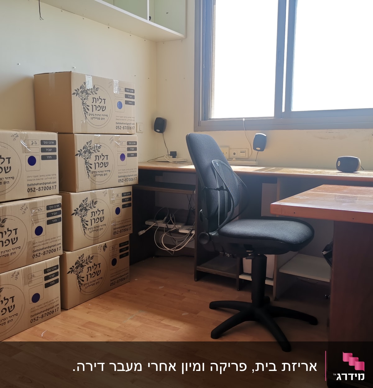 חדר עם קופסאות קרטון מסודרות על הרצפה ליד שולחן עבודה